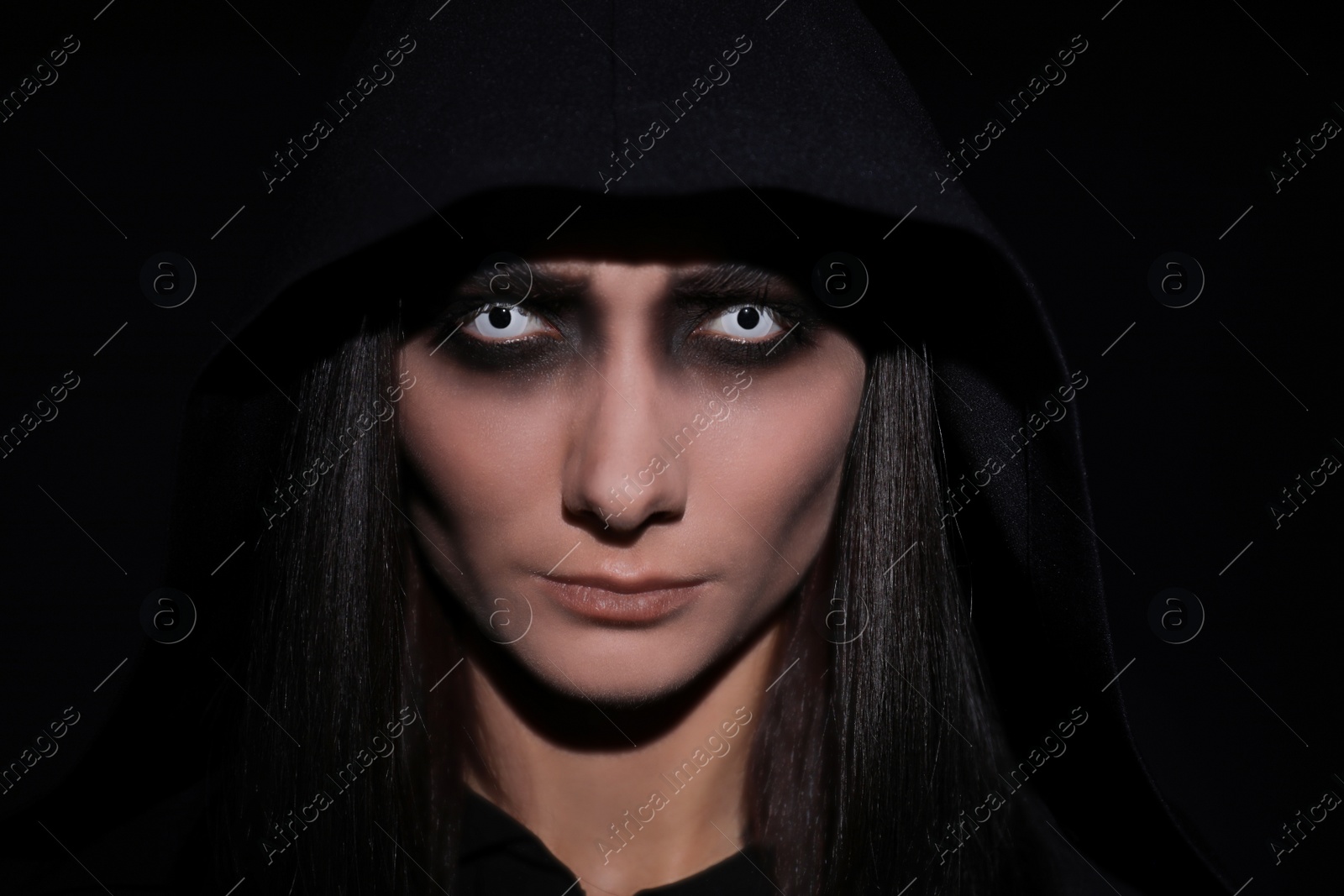Photo of Mysterious witch with spooky eyes on black background