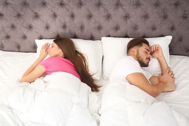 Photo of Young couple sleeping back to back in bed at home. Relationship problems