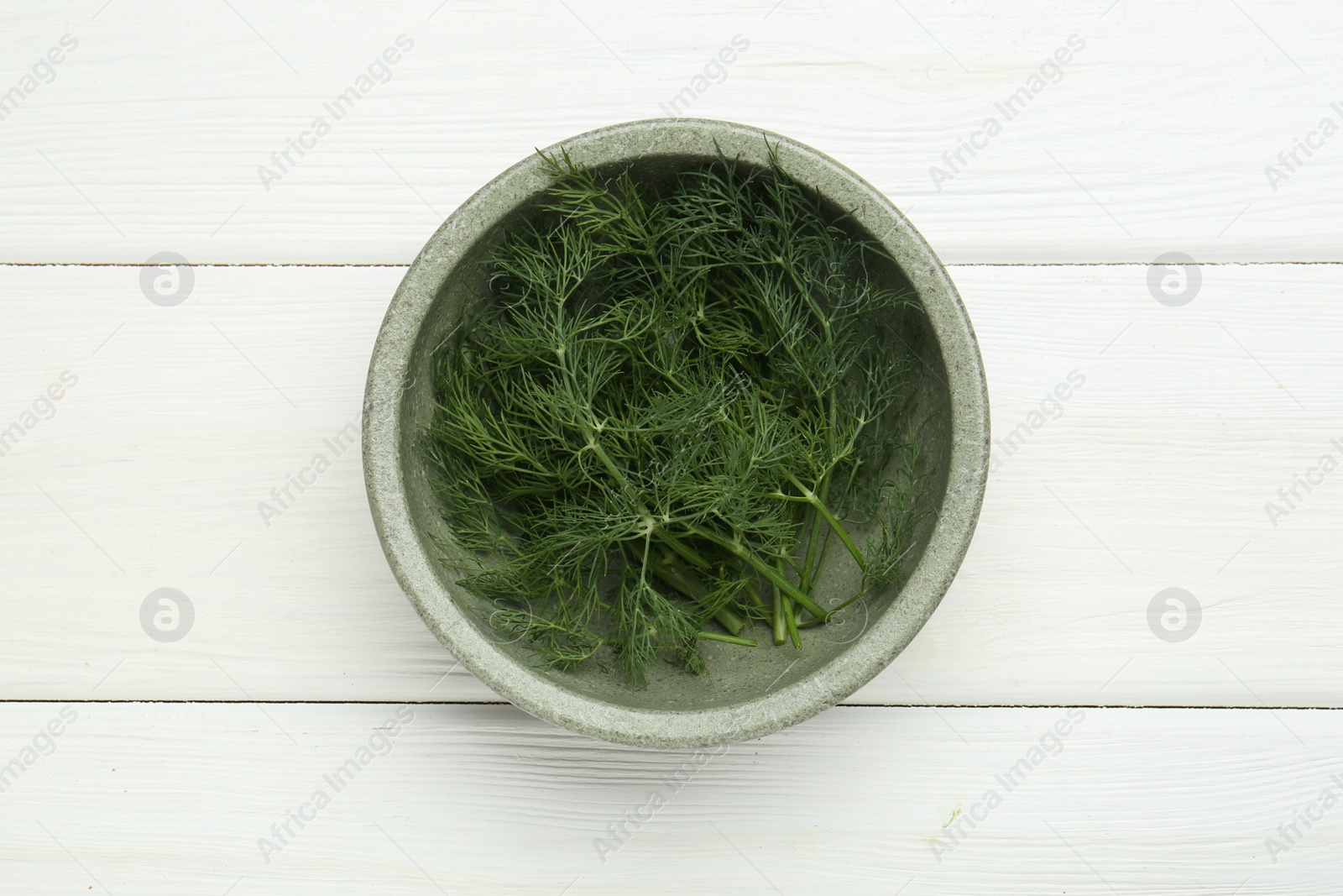 Photo of Bowl of fresh green dill on white wooden table, top view
