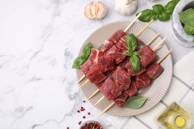 Photo of Flat lay composition with cut fresh beef meat on white marble table. Space for text
