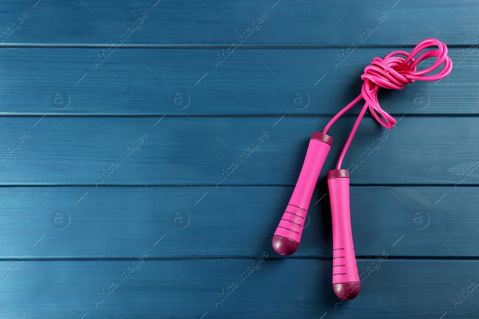 Photo of Skipping rope on blue wooden table, top view. Space for text