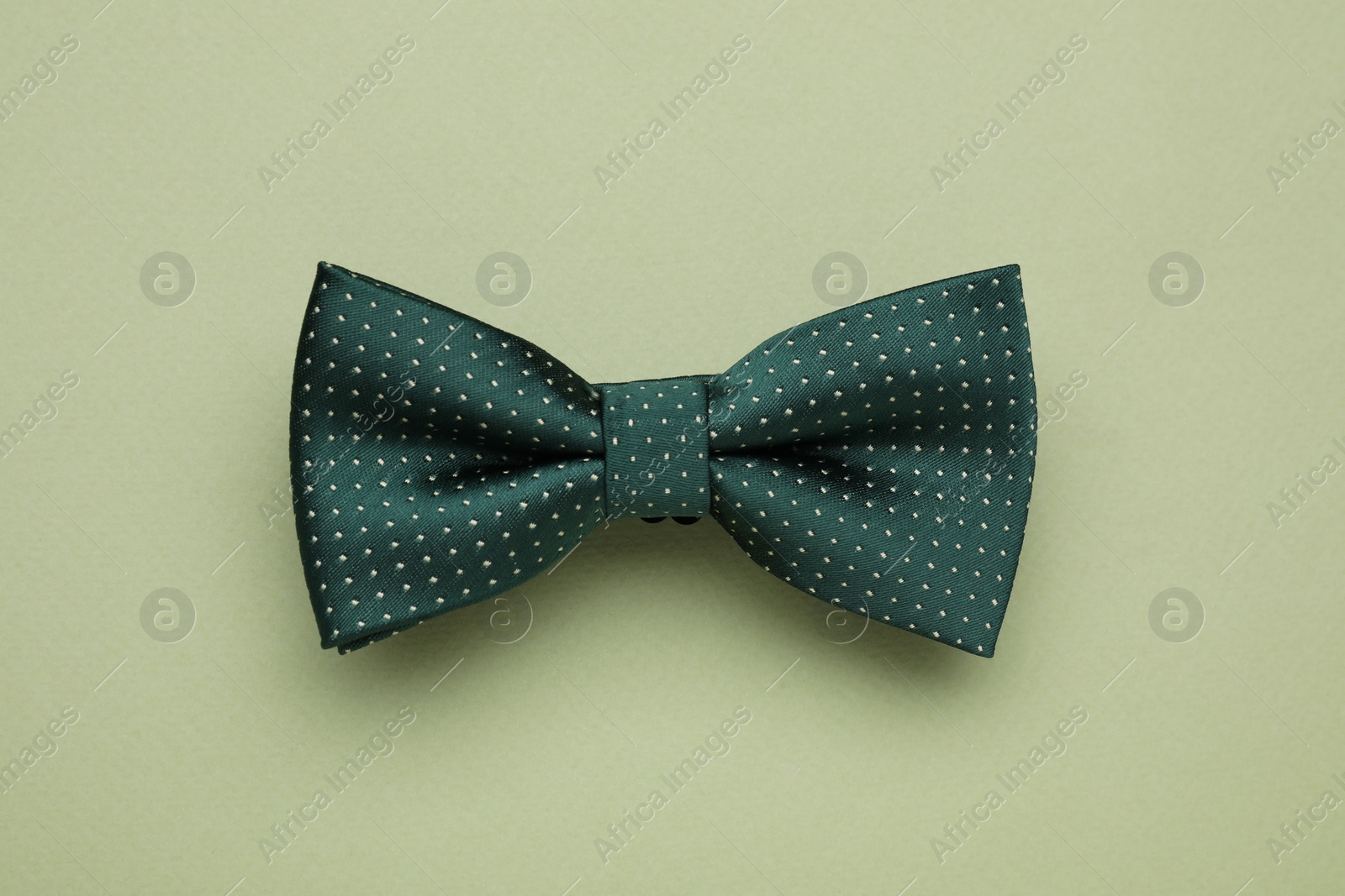 Photo of Stylish bow tie with polka dot pattern on pale green background, top view