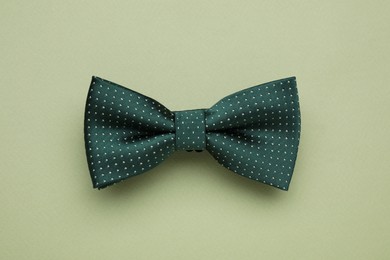 Stylish bow tie with polka dot pattern on pale green background, top view