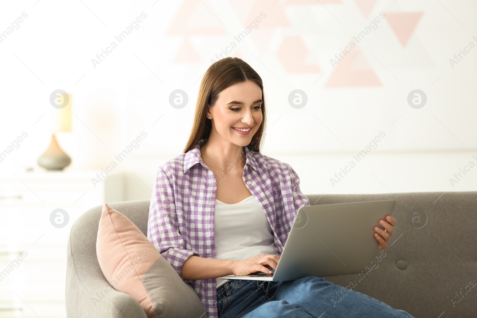 Photo of Young woman using modern laptop at home