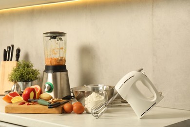 Photo of Modern mixer, blender and different ingredients on white marble countertop