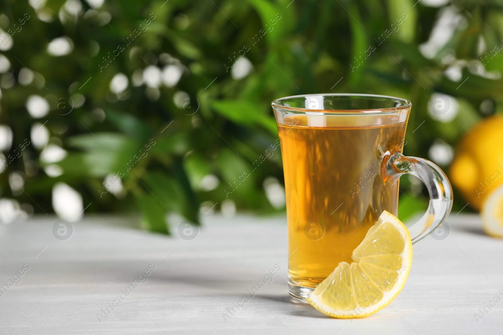 Photo of Glass cup of hot tea with lemon on white table