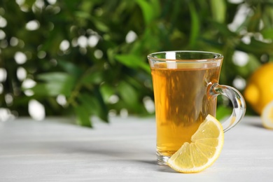 Glass cup of hot tea with lemon on white table