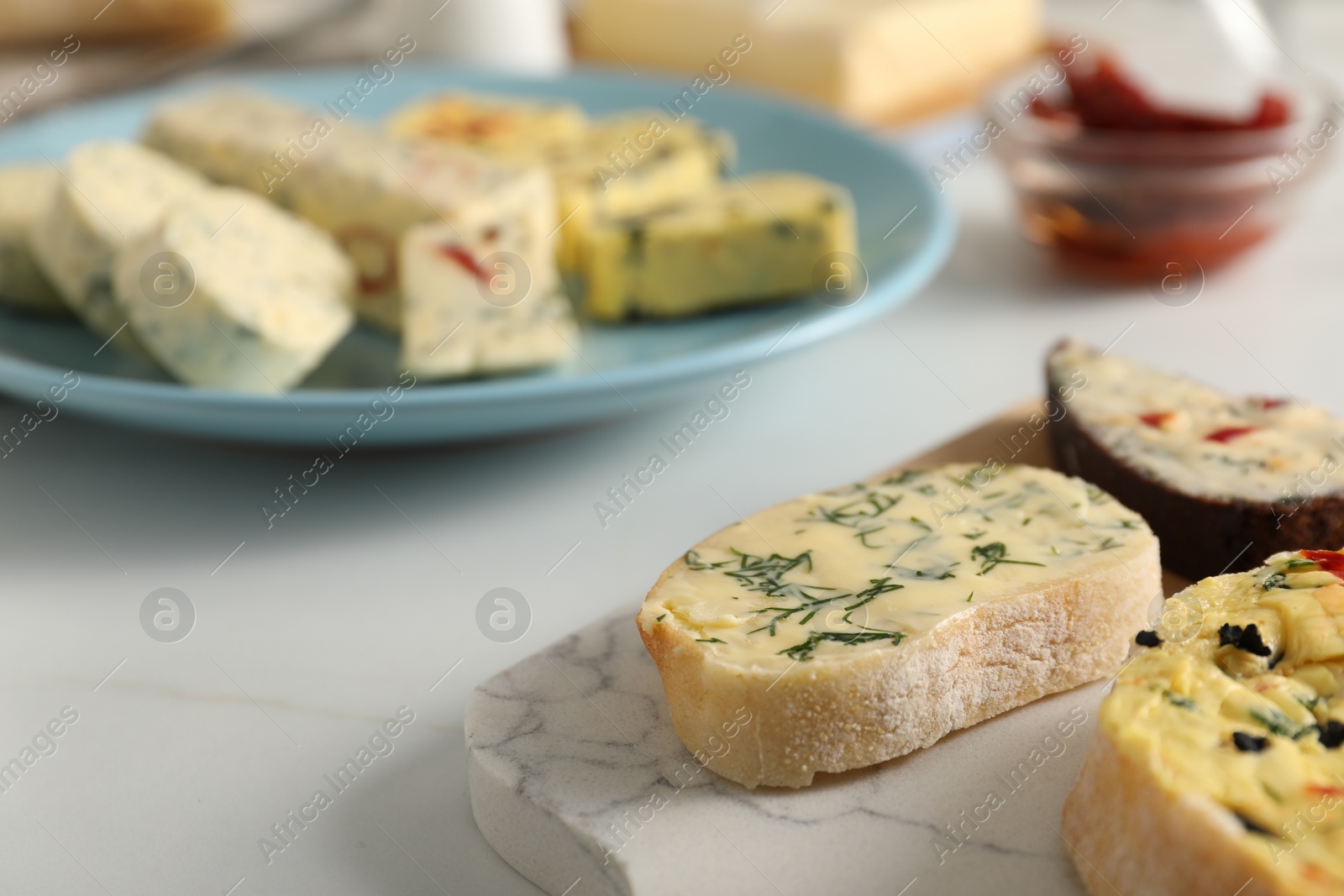 Photo of Different types of tasty butter and bread on white table, closeup