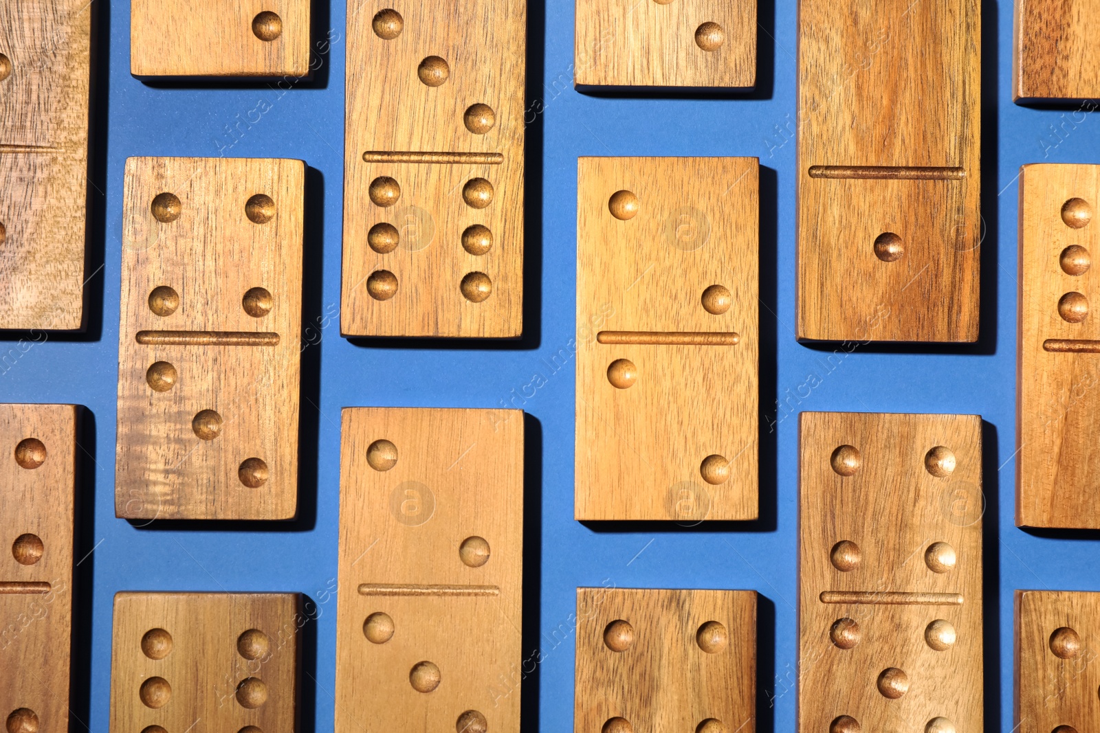 Photo of Set of wooden domino tiles on blue background, flat lay