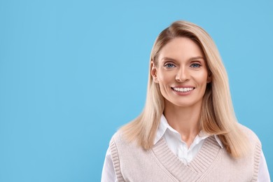 Photo of Portrait of smiling middle aged woman on light blue background. Space for text