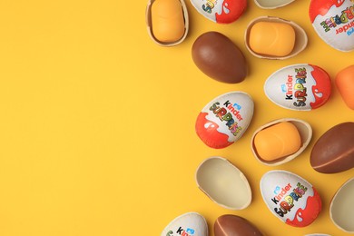 Sveti Vlas, Bulgaria - June 29, 2023: Kinder Surprise Eggs and plastic capsules on orange background, flat lay. Space for text