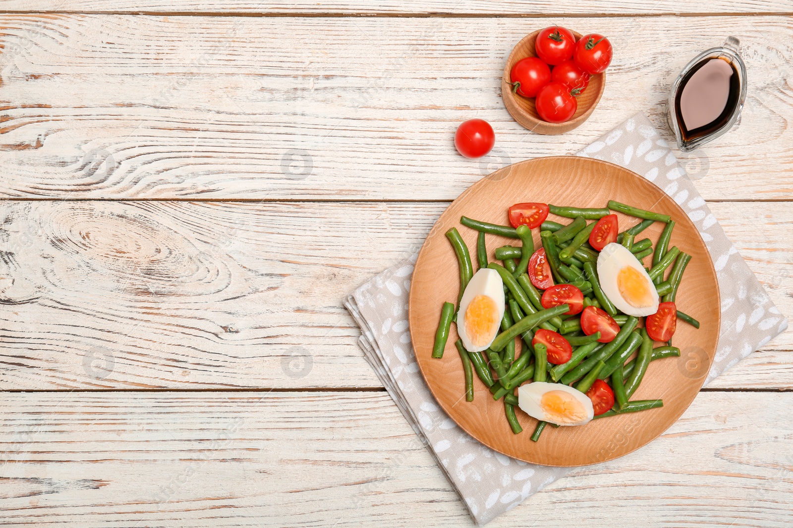 Photo of Plate with tasty green beans, eggs and  tomatoes on wooden table, top view