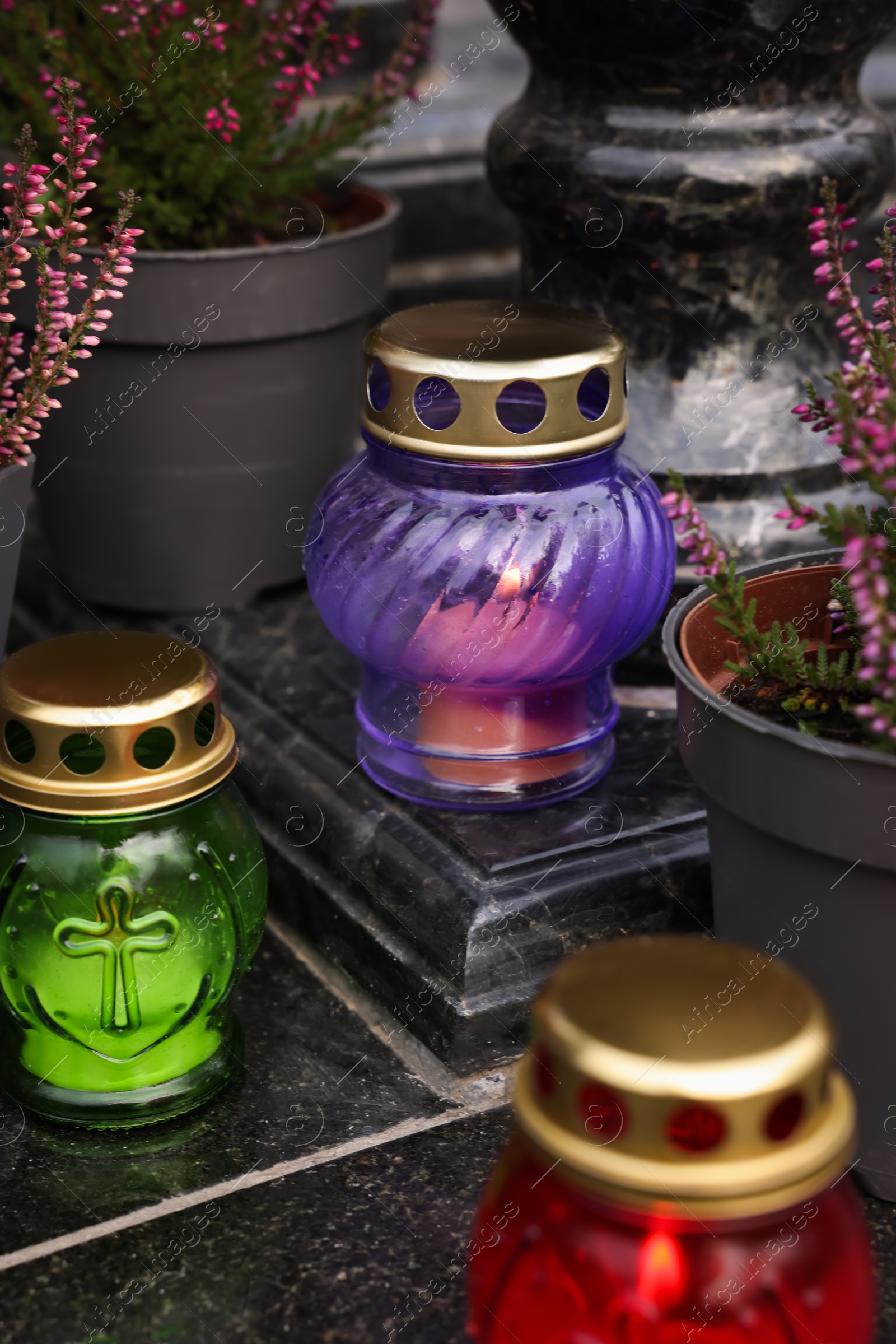 Photo of Different grave lanterns on granite surface at cemetery