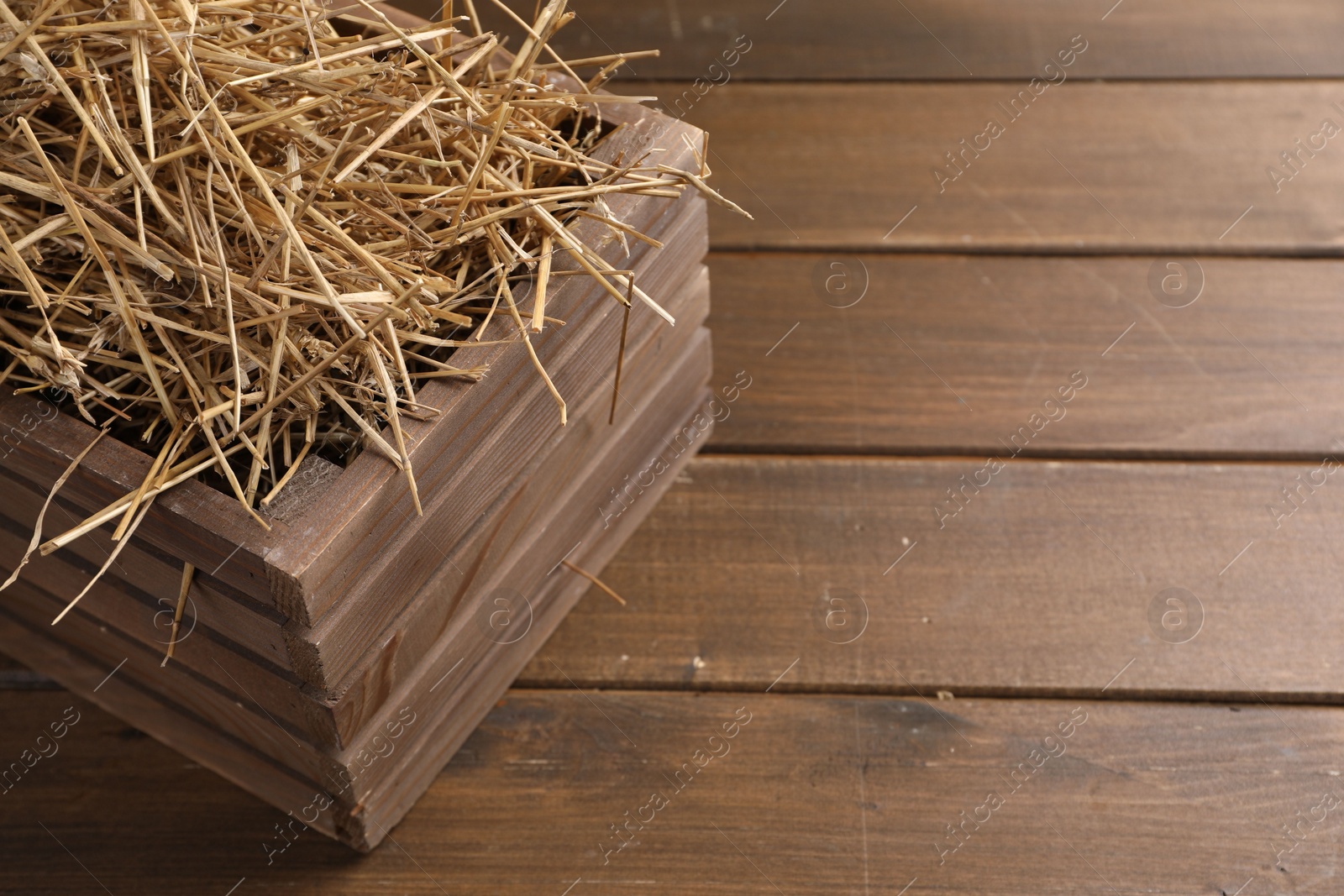 Photo of Dried straw in crate on wooden table, space for text