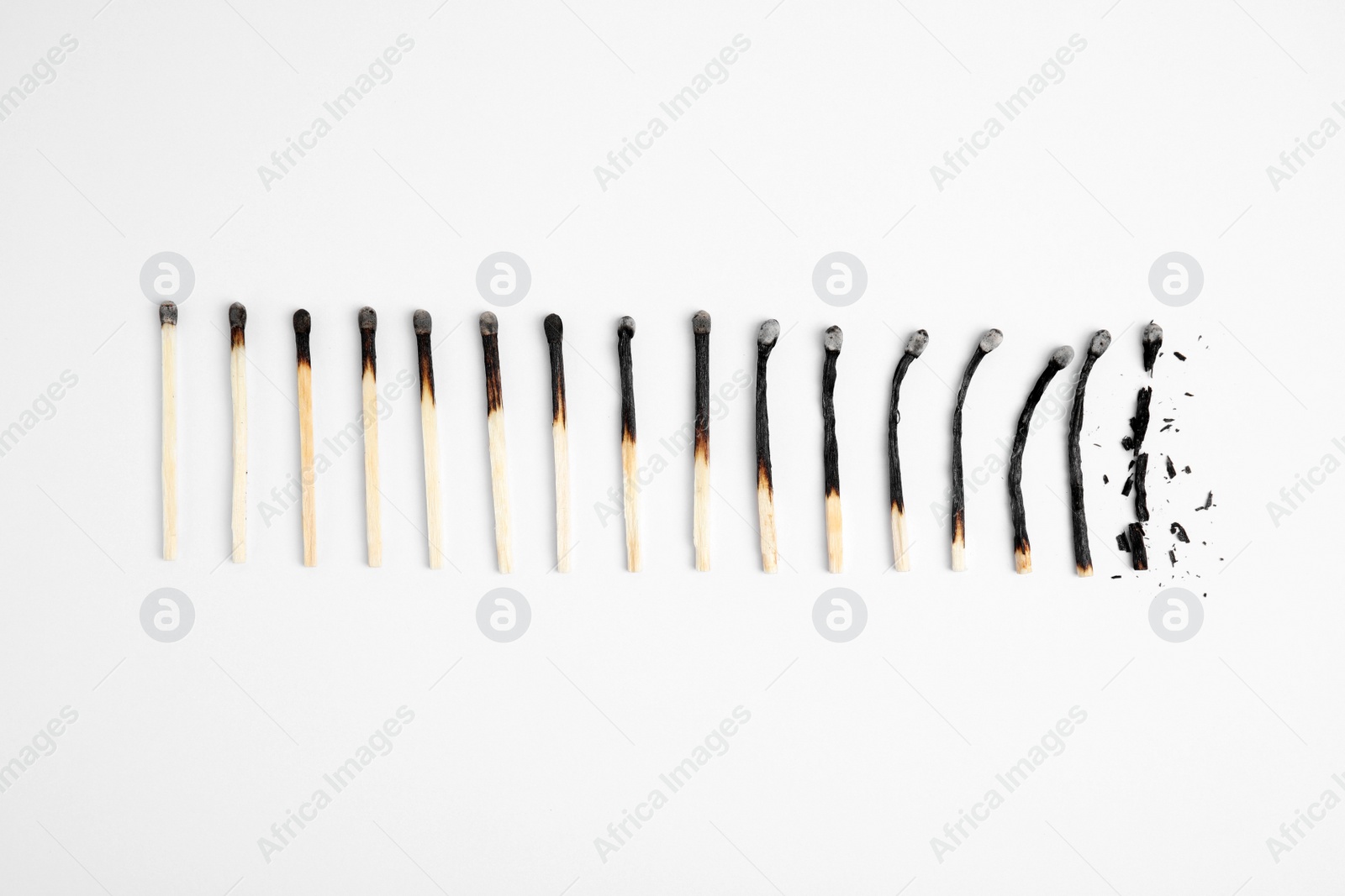 Photo of Different stages of burnt matches on white background, flat lay