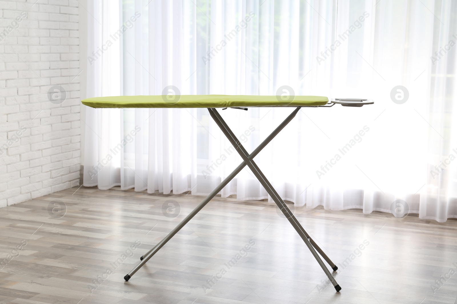 Photo of Modern empty ironing board near window at home