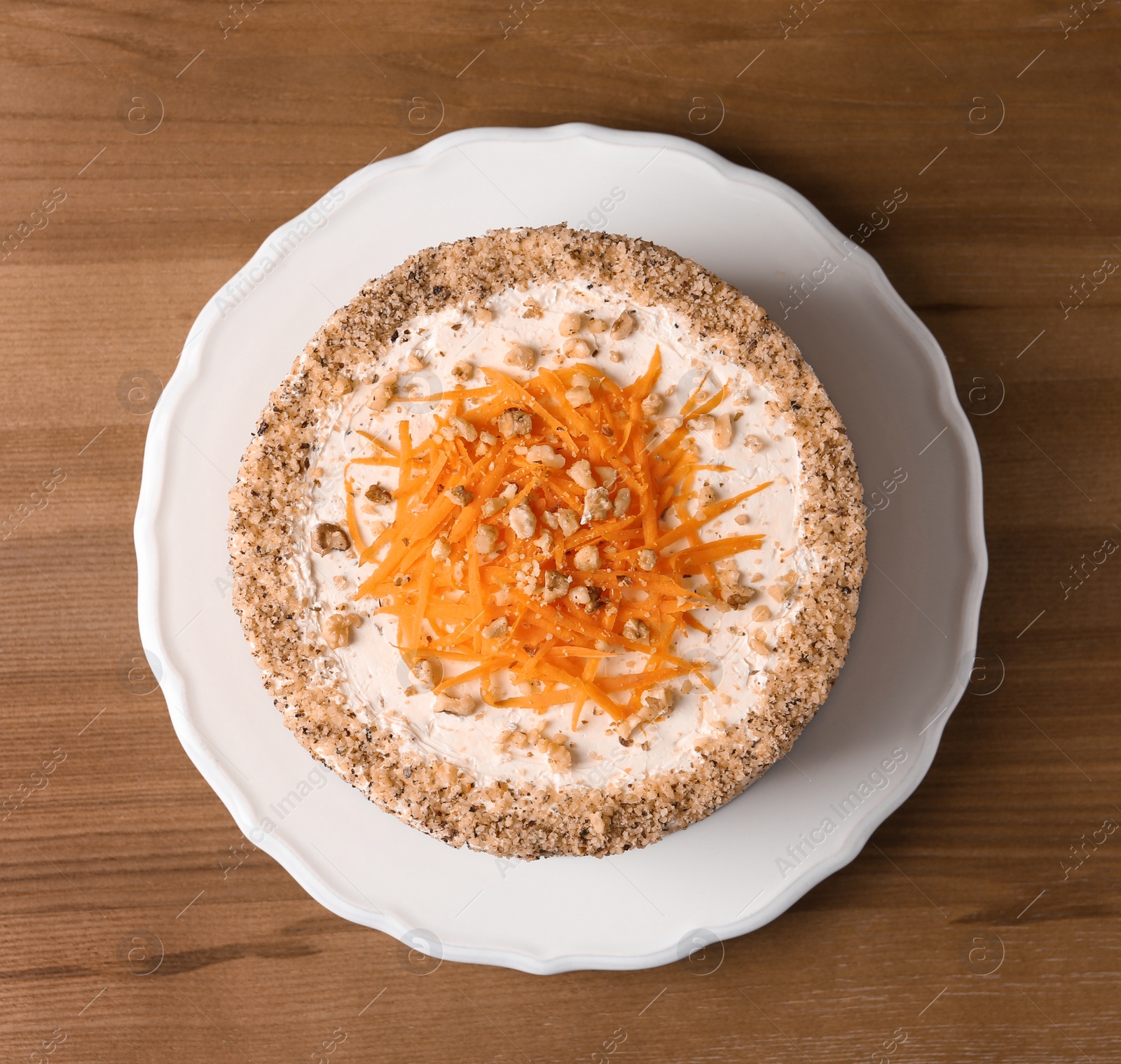 Photo of Sweet carrot cake with delicious cream on wooden table, top view