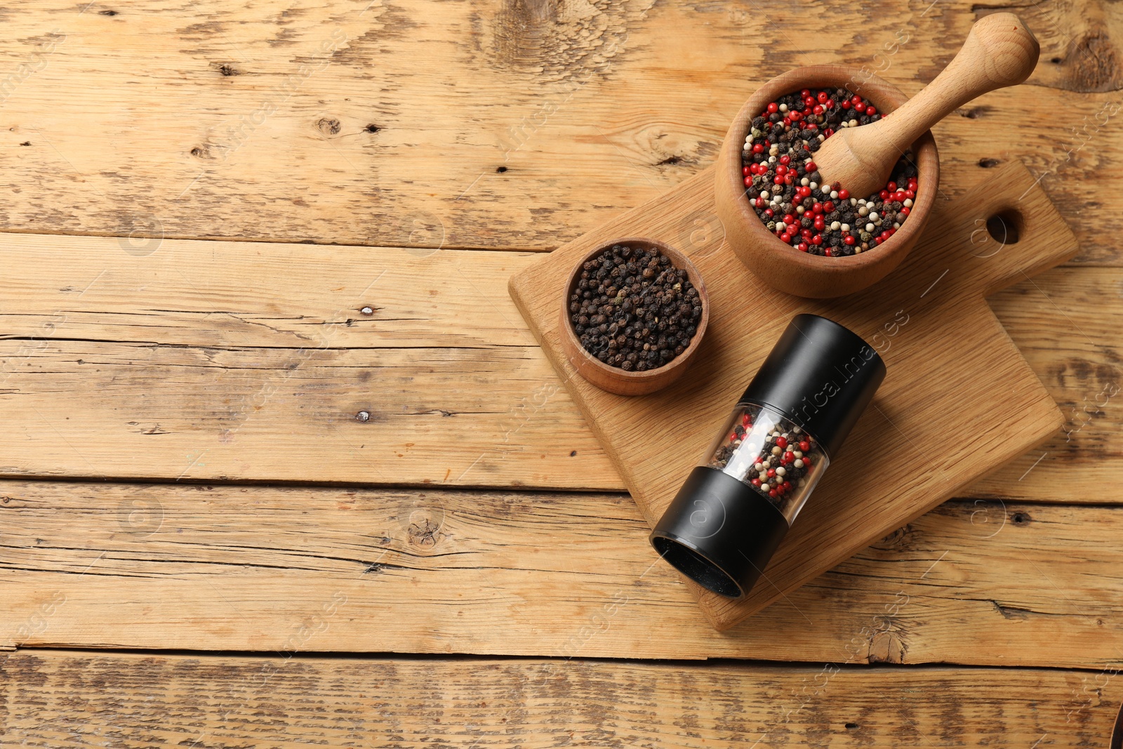 Photo of Different peppercorns on wooden table, flat lay. Space for text