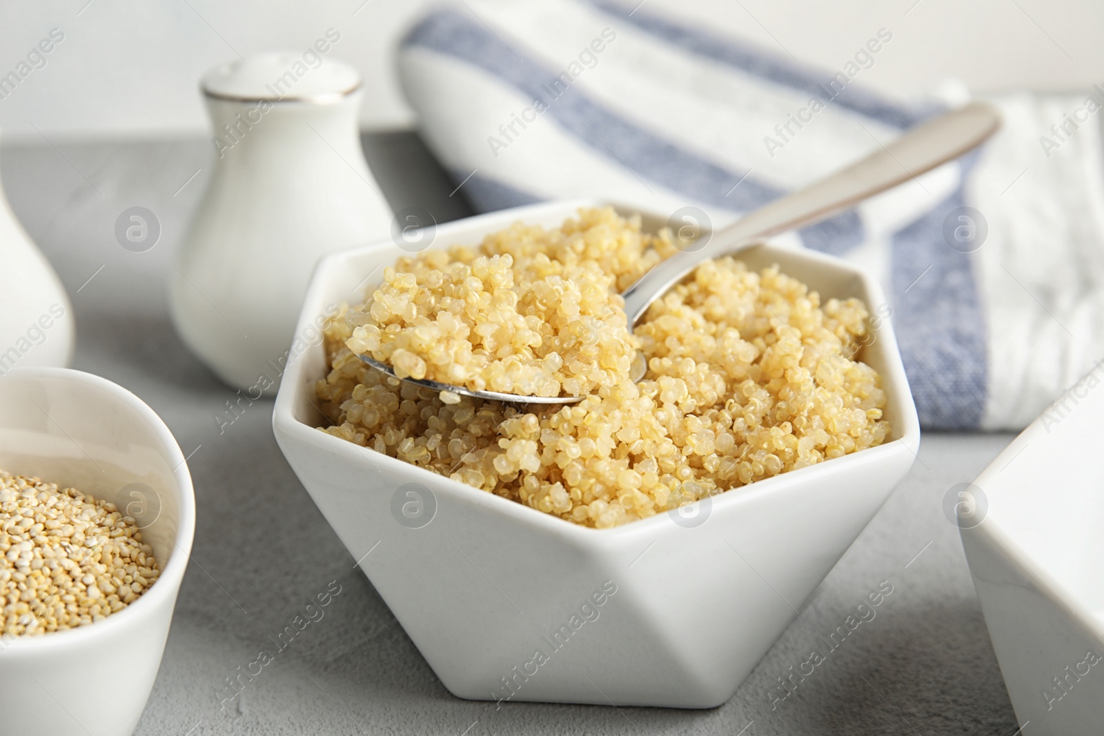 Photo of Composition with cooked quinoa in white ceramic bowl on table