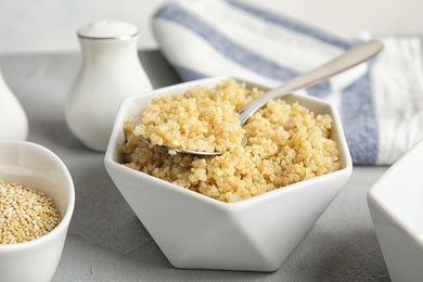 Composition with cooked quinoa in white ceramic bowl on table