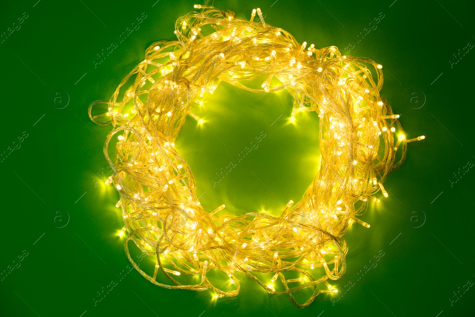 Photo of Frame made of glowing Christmas lights on green background, top view