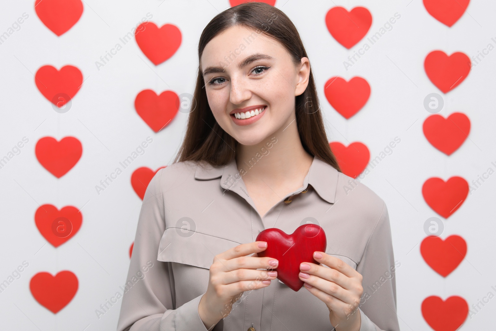 Photo of Smiling woman holding red heart on decorated background