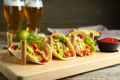 Photo of Delicious tacos with guacamole, meat and vegetables served on wooden table