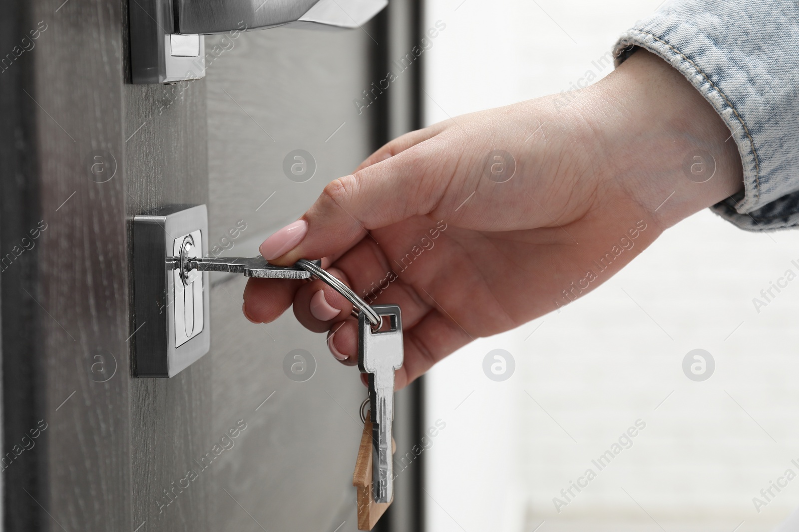 Photo of Woman unlocking door with key, closeup view