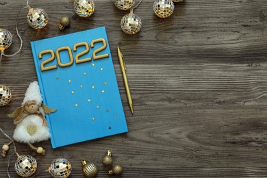 Photo of Planner and Christmas decor on wooden background, flat lay with space for text. 2022 New Year aims