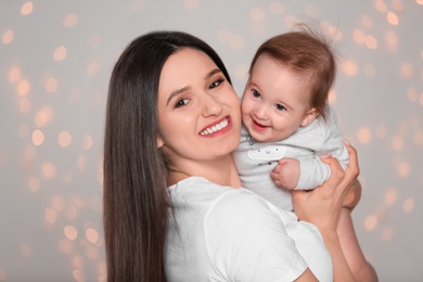 Photo of Portrait of young mother and her adorable baby against defocused lights