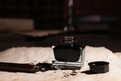Photo of Inkwell and fountain pen on vintage parchment, closeup
