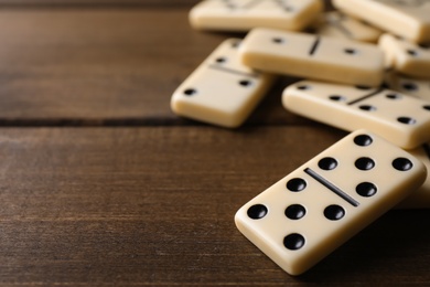 Domino tiles on wooden table, closeup. Space for text