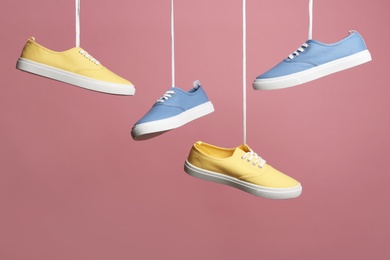 Photo of Bright stylish shoes hanging against color background