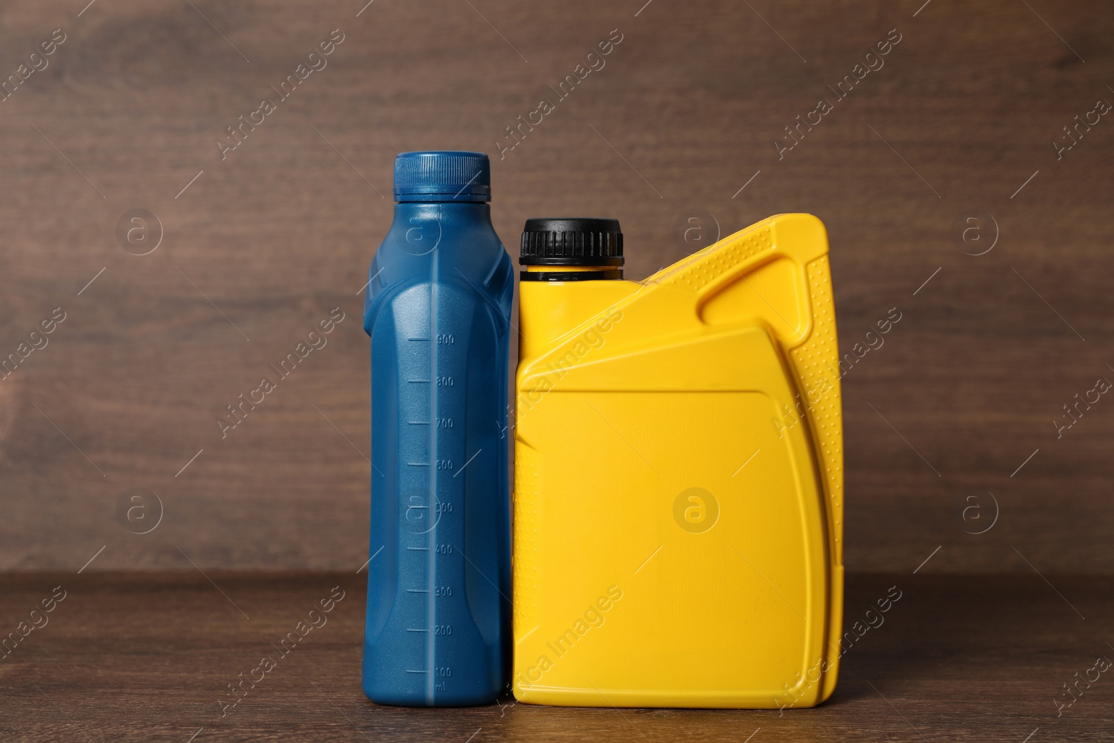 Photo of Motor oil in different canisters on wooden background