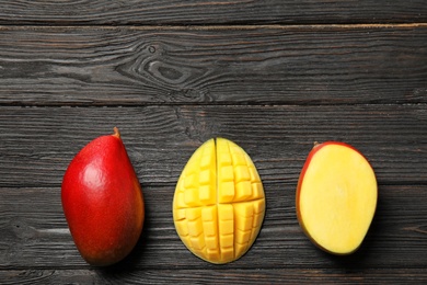 Flat lay composition with ripe mangoes and space for text on wooden background