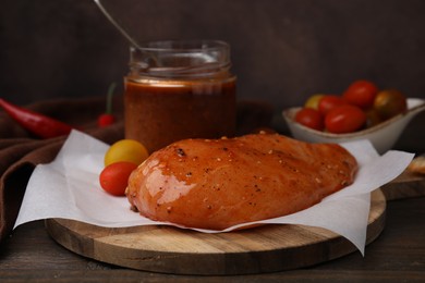 Photo of Fresh marinade and raw chicken fillets on wooden table