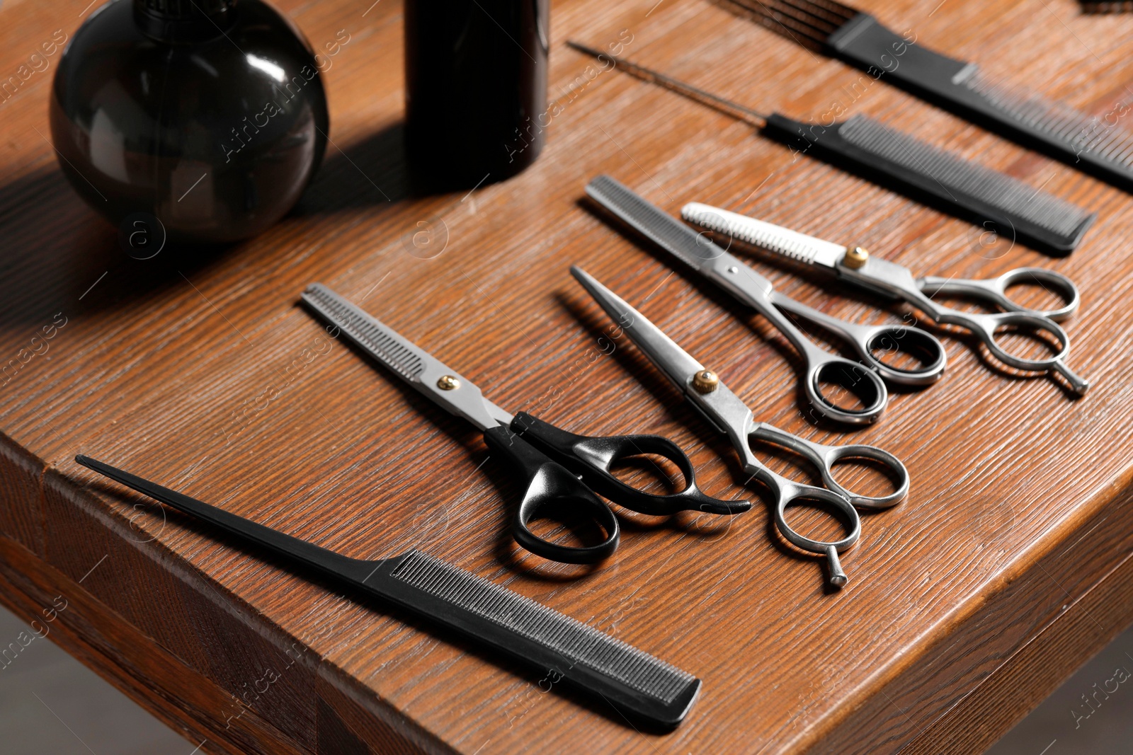 Photo of Hairdresser tools. Different scissors and combs on wooden table, closeup