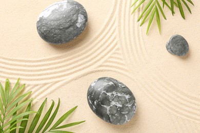 Photo of Zen concept. Stones, leaves and pattern on beige sand, flat lay