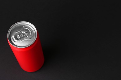 Energy drink in red can on black background, above view. Space for text