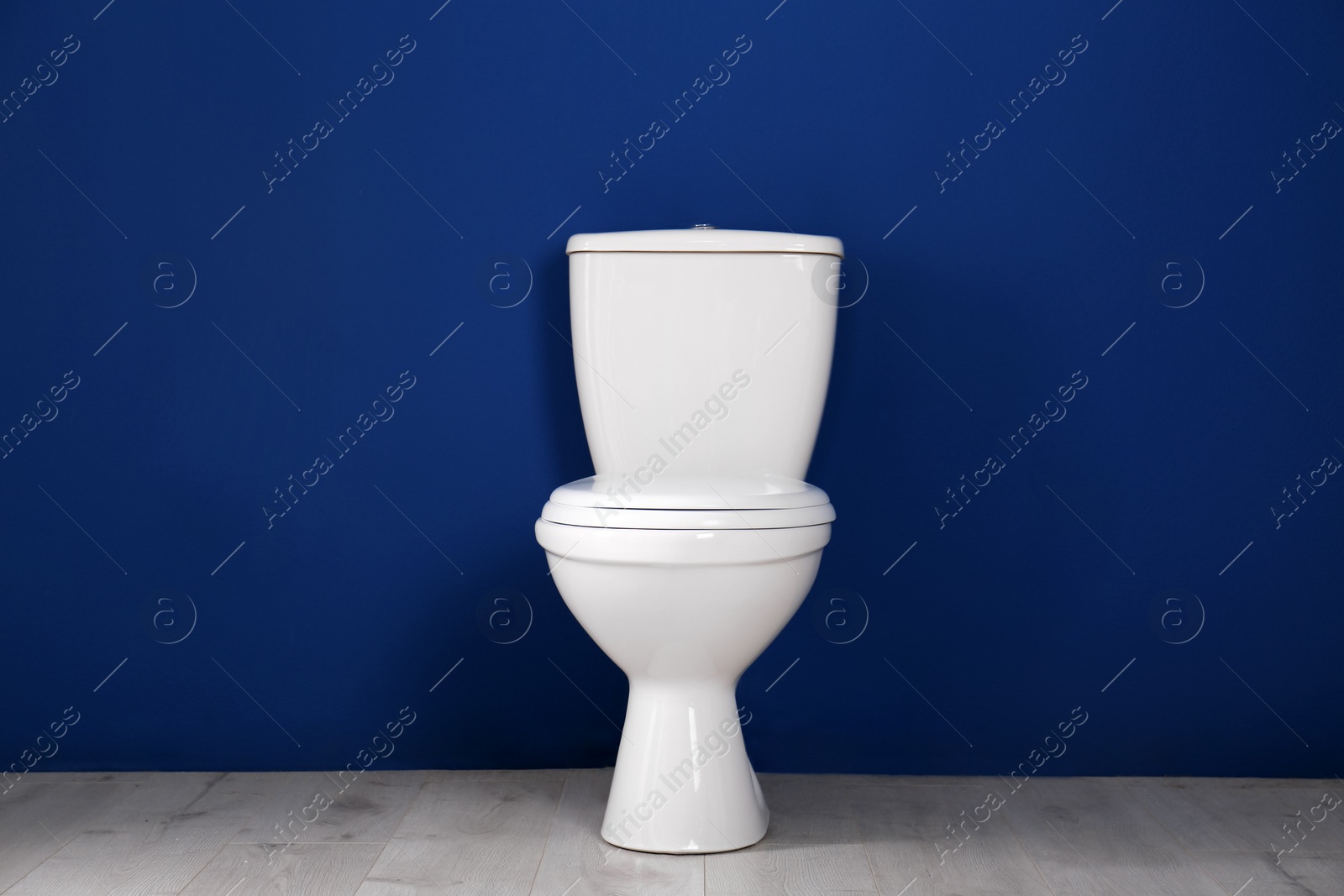 Photo of New toilet bowl near color wall indoors