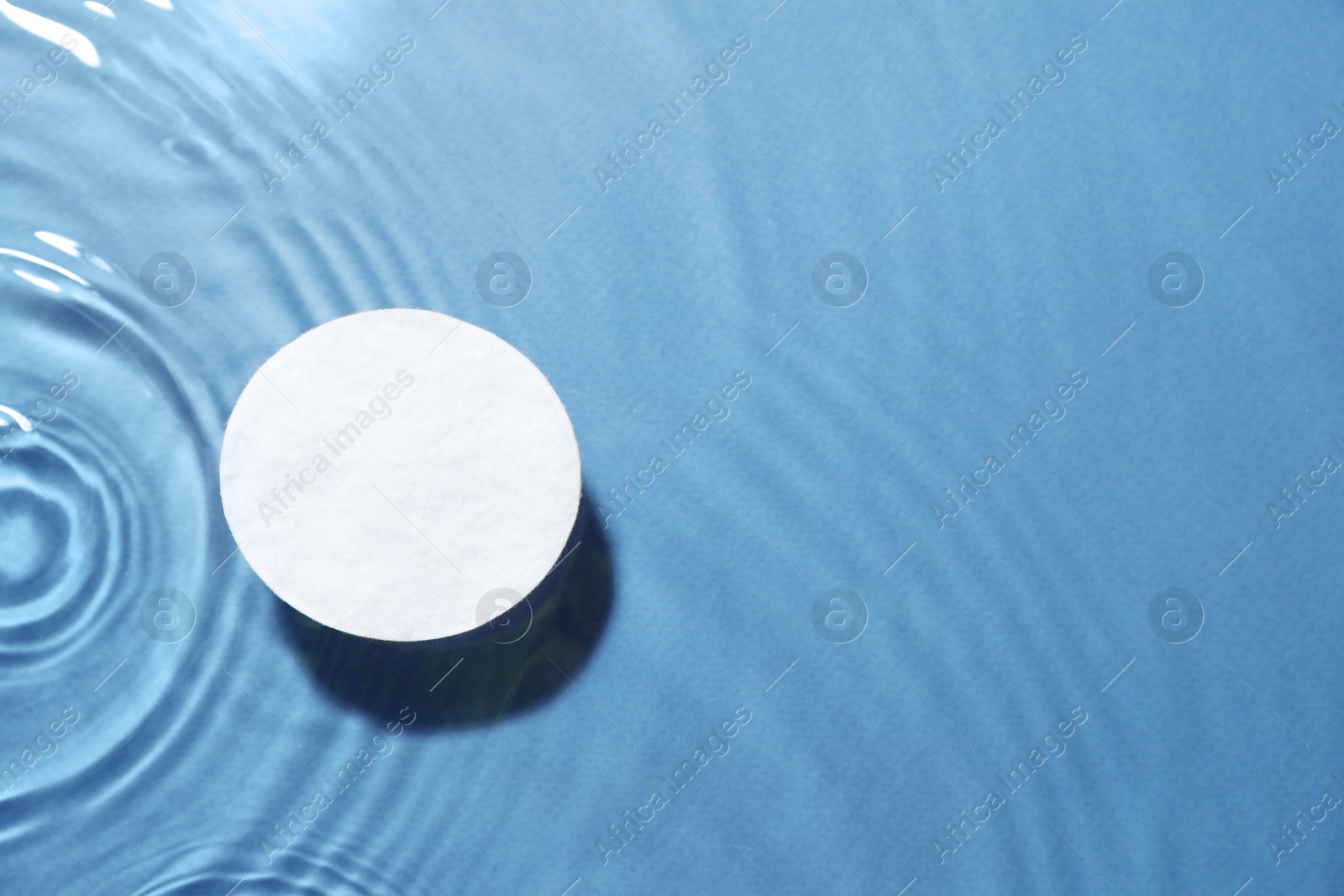 Image of Cotton pad in micellar water on light blue background, above view. Space for text