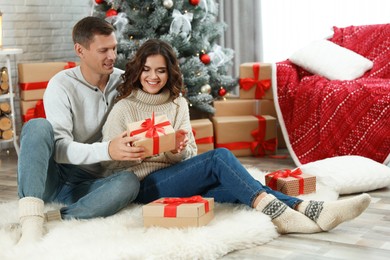 Image of Man presenting Christmas gift to his girlfriend at home 