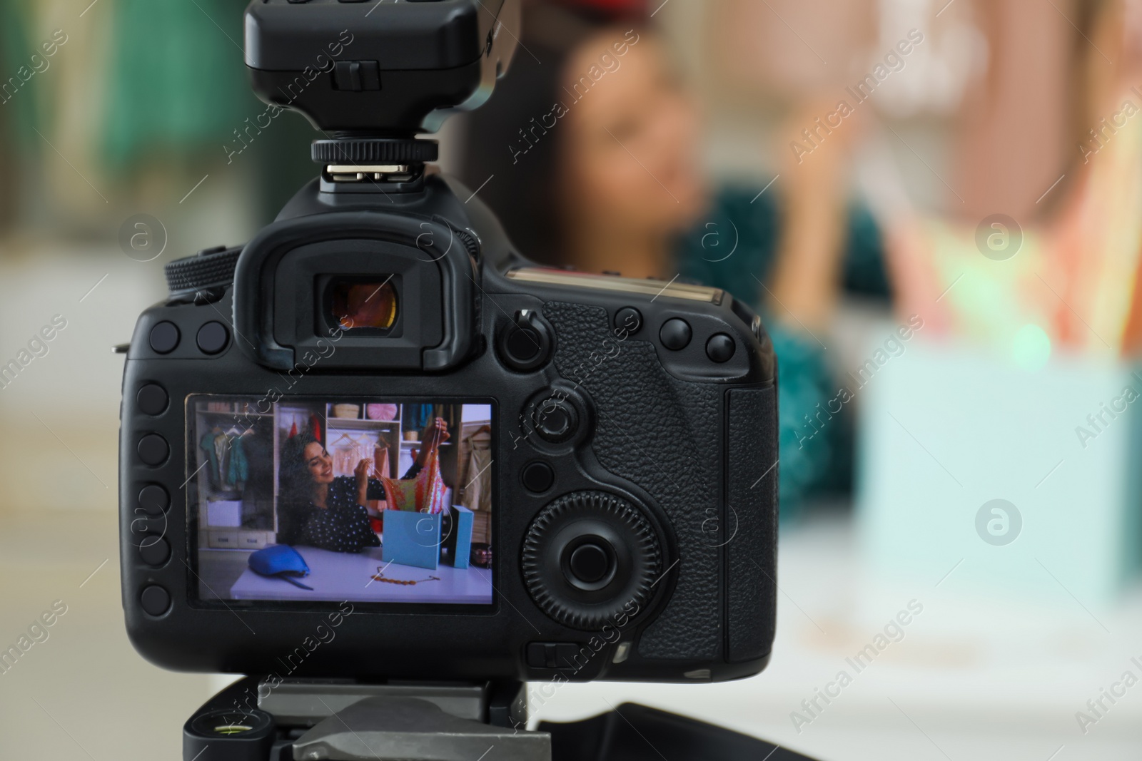 Photo of Fashion blogger recording new video at table indoors, focus on camera