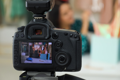 Fashion blogger recording new video at table indoors, focus on camera