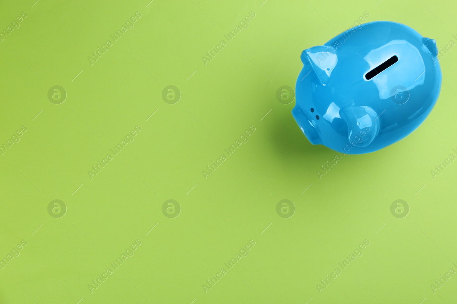 Photo of Blue piggy bank on green background, top view. Space for text