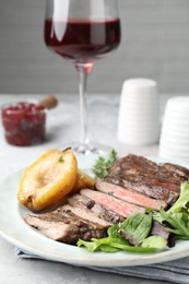 Photo of Delicious roasted beef meat, caramelized pear and greens served on table, closeup