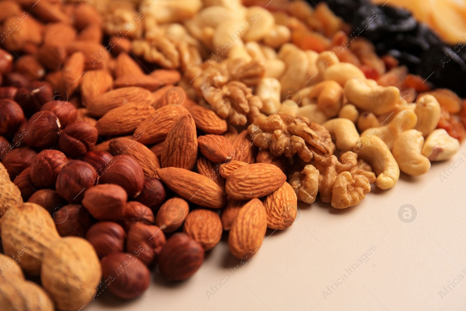 Photo of Mix of delicious dried nuts on beige background, closeup