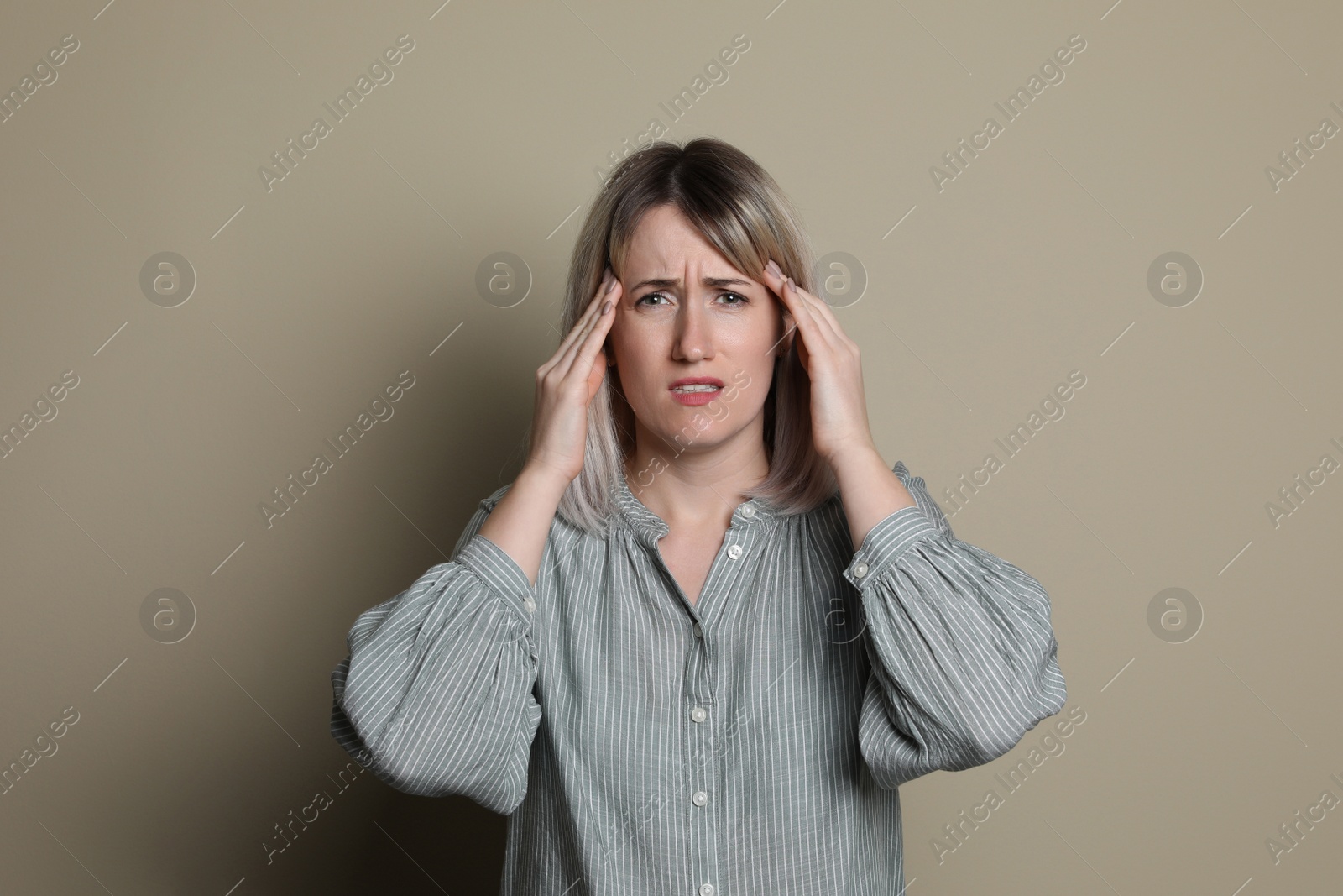 Photo of Woman suffering from headache on beige background