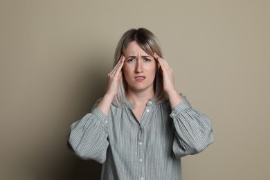 Photo of Woman suffering from headache on beige background