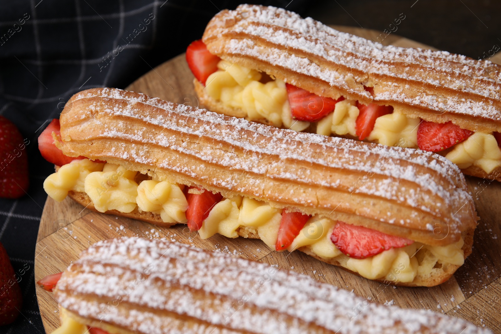 Photo of Delicious eclairs filled with cream and strawberries on table, closeup